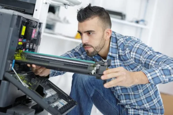 Technicien RLS en intervention sur un photocopieur professionnel